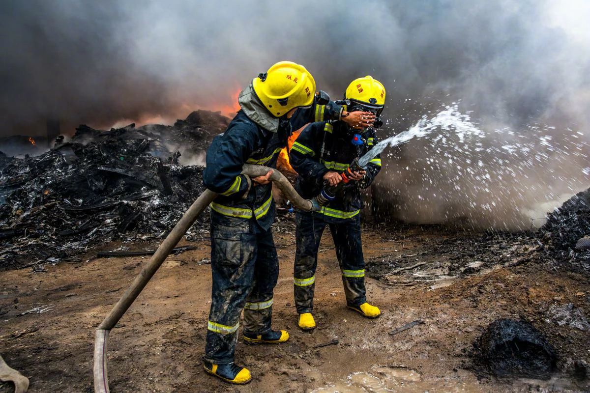 Firefighters in full bunker gear are putting out a fire.